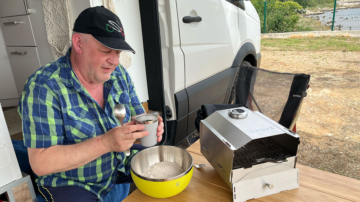 8 Koch-Tools für unterwegs – unsere Favoriten 1 Ein Mann kocht mit Koch-Tools vor einem Campervan draußen