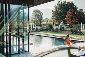 Kuriose neue Reiseportale 1 Mann sitzt am Pool am Hotel in den Alpen