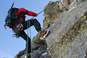 Mann hängt draußen an einer Kletterwand