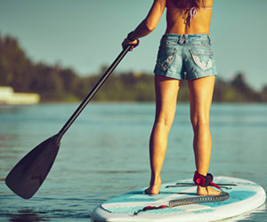 Frauenbeine von hinten auf Stand-up-Paddel