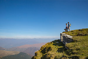 2 Menschen und ein Hund stehen in der Bergwelt der Schweiz