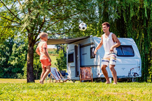 Fahrzeug mieten, einsteigen, Urlaub genießen 1 Mann und Sohn spielen Fußball vor einem Wohnmobil