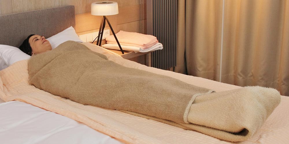 Frau eingewickelt in Laken während Schorthkurpackung