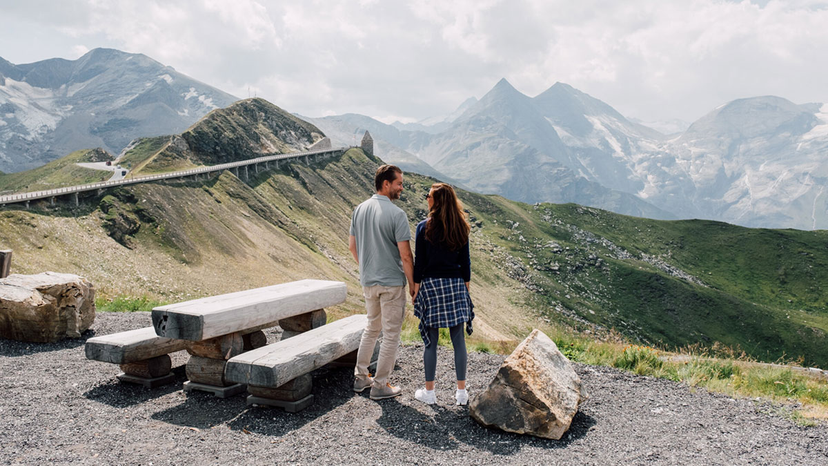 Staufrei über den Großglockner: In 2024 gilt ein Sondertarif für den An- und Abreisetag 6 Paar macht Pause am Großglockner auf dem Weg in den Urlaub