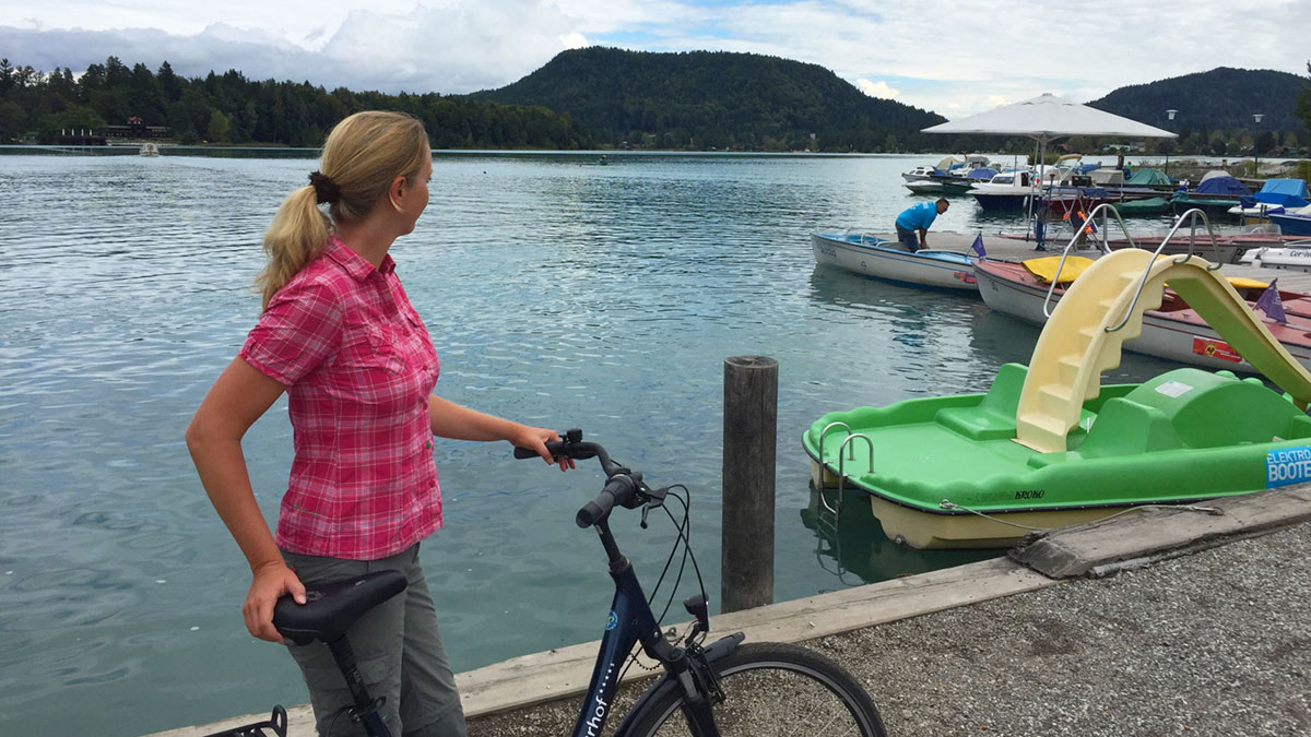 Erst schwitzen, dann im Faaker See baden 3 Eine Frau steht mit einem Fahrrad vor dem Faaker See