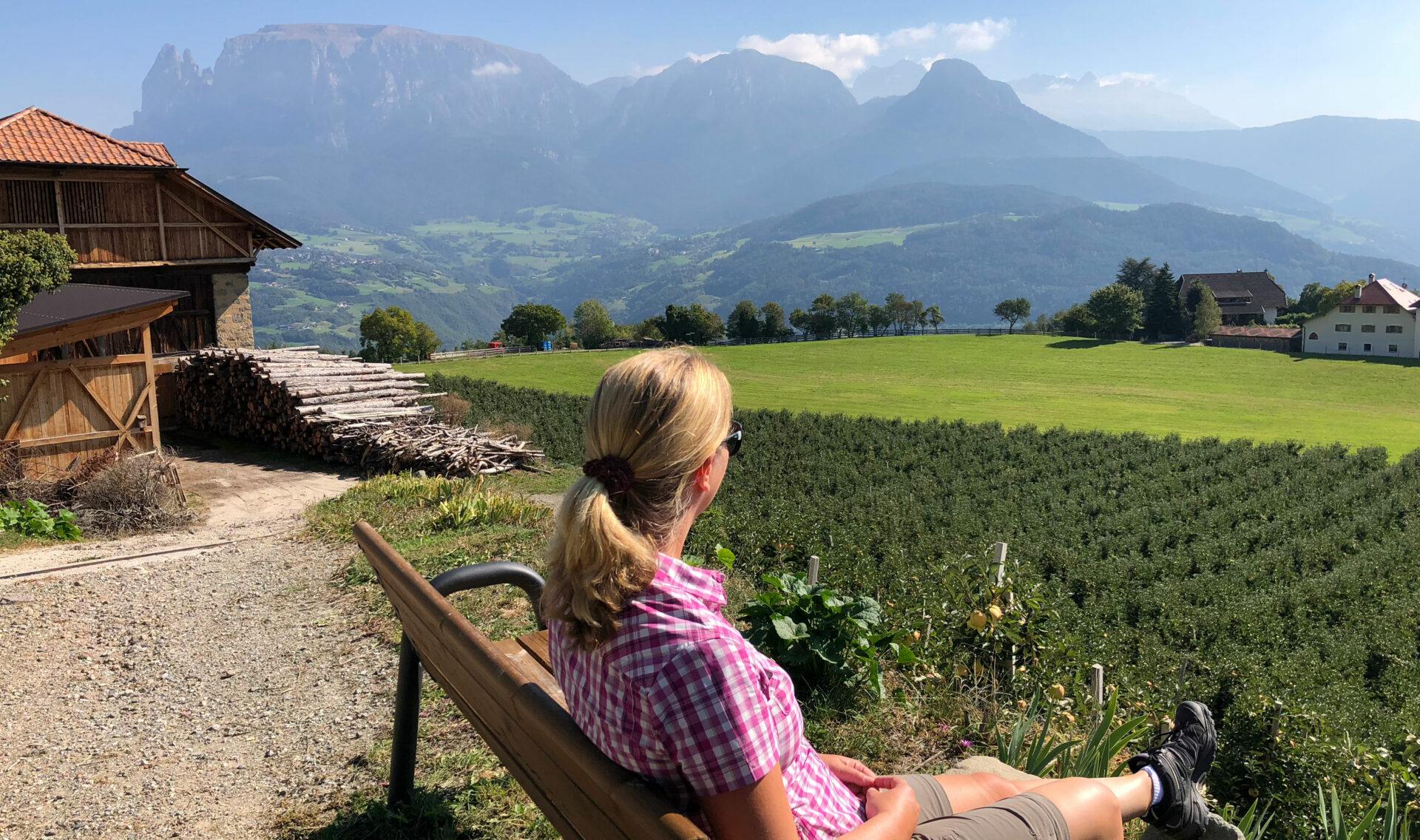 Herbstwanderung auf dem Keschtnweg durch Südtirol 3 Eine Wanderin sitzt auf einer Bank in den Dolomiten und genießt den Ausblick auf die Dolomiten