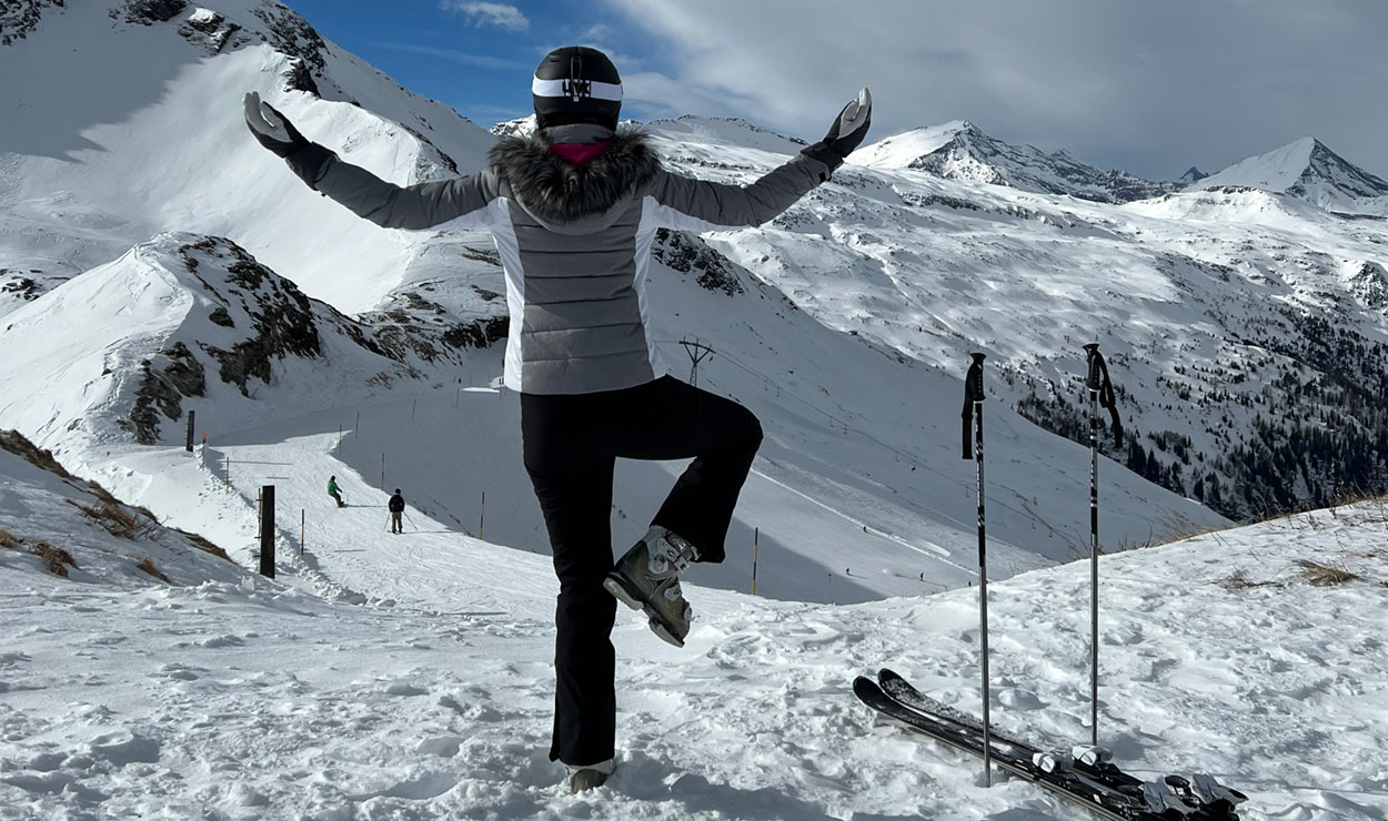 Schnee-Yoga: Bewusste Auszeit im Winterwunderland 2 Eine Skifahrerin macht auf der Piste Yoga-Übungen