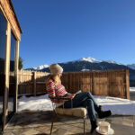 JOMO-Urlaub: Die Kunst des Nichtstuns 10 Frau sitzt lesend auf der Terrasse in der Wintersonne