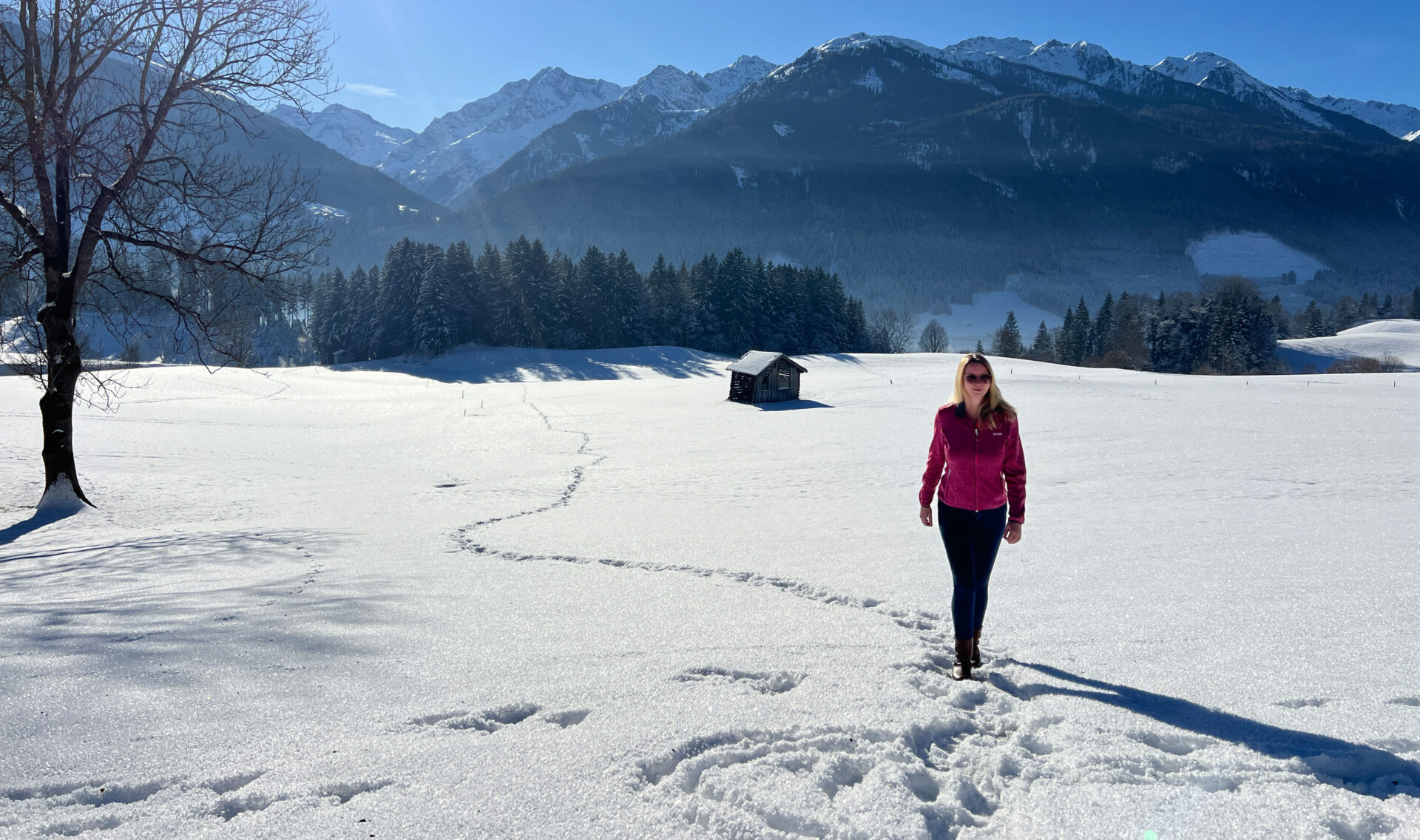 JOMO-Urlaub: Die Kunst des Nichtstuns 2 Frau spaziert durch die Winterlandschaft durch Neuschnee