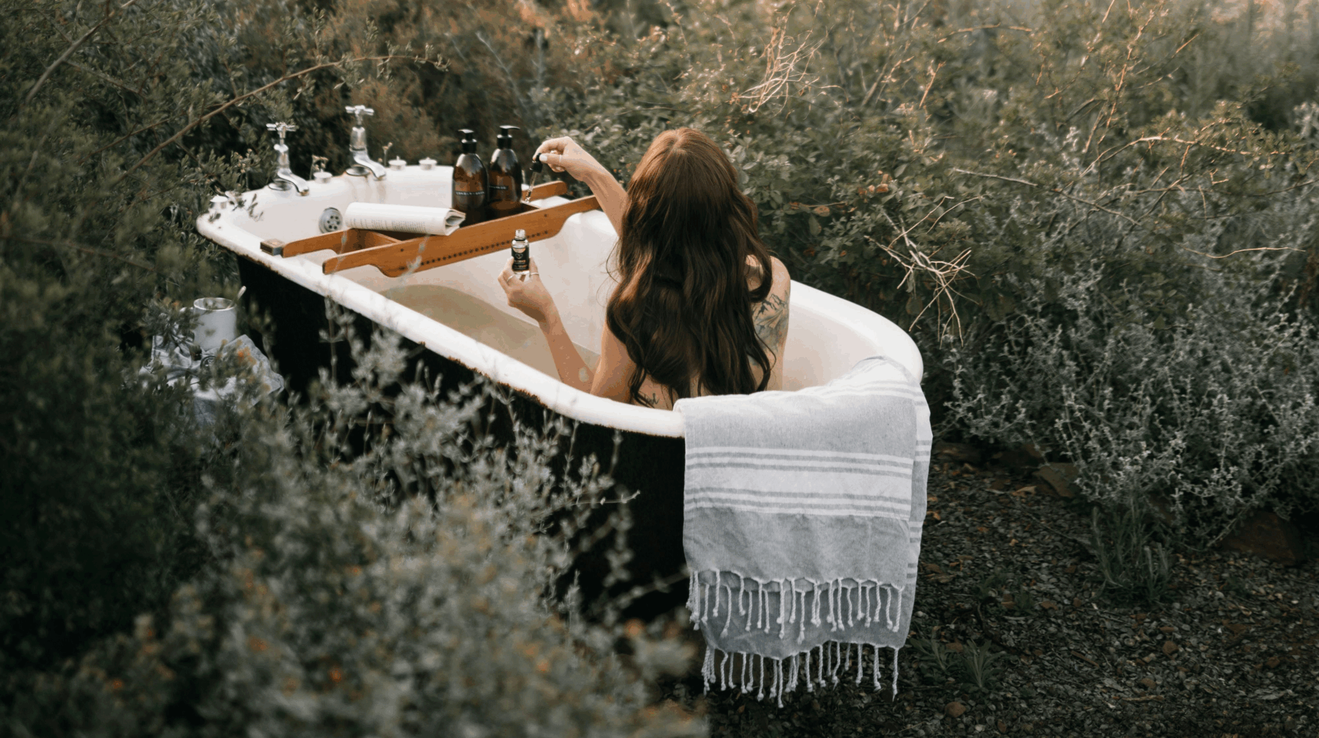 4 x Outdoor-Hygiene für unterwegs 21 Eine Frau mit langen Haaren sitzt im Freien in einer Badewanne