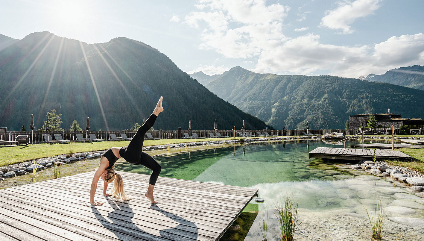 15 Erholungsorte, die Stil und Zeitgeist atmen 2 Eine blonde Frau macht Yoga vor Alpenkulisse