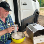 8 Koch-Tools für unterwegs – unsere Favoriten 5 Ein Mann kocht mit Koch-Tools vor einem Campervan draußen