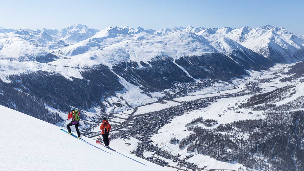 Olympia 2026 Livigno: Zurück in die Zukunft 5 Blick auf zwei Männer auf Skiern, die auf die Straße unter dme Berg schauen