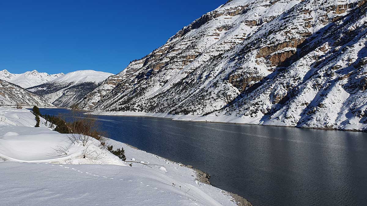 Olympia 2026 Livigno: Zurück in die Zukunft 3 Der Stausee Lago di Livigno umgeben von schneebedeckten Bergen und Flächen